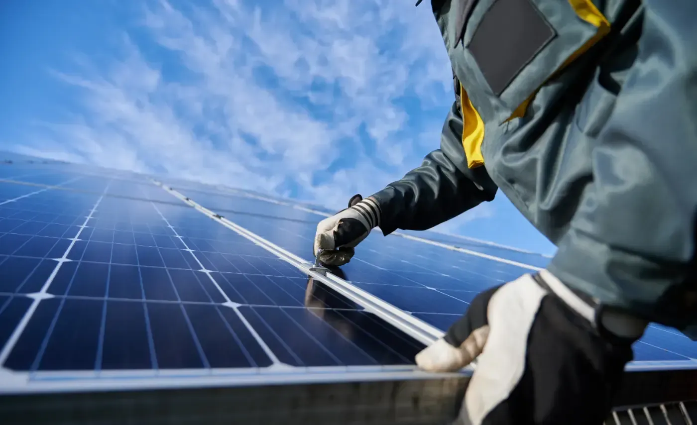 Ein Mann installiert Solarmodule auf einem Dach.