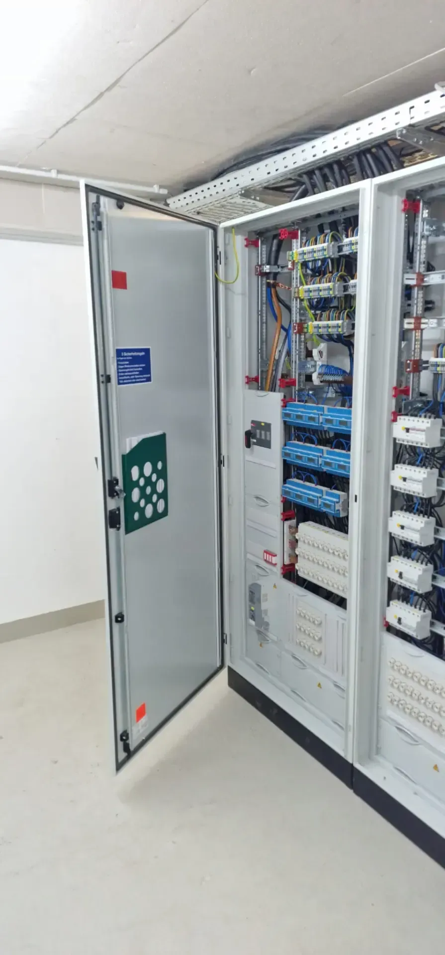 Ein großer Schaltschrank mit offener Tür in einem Raum.