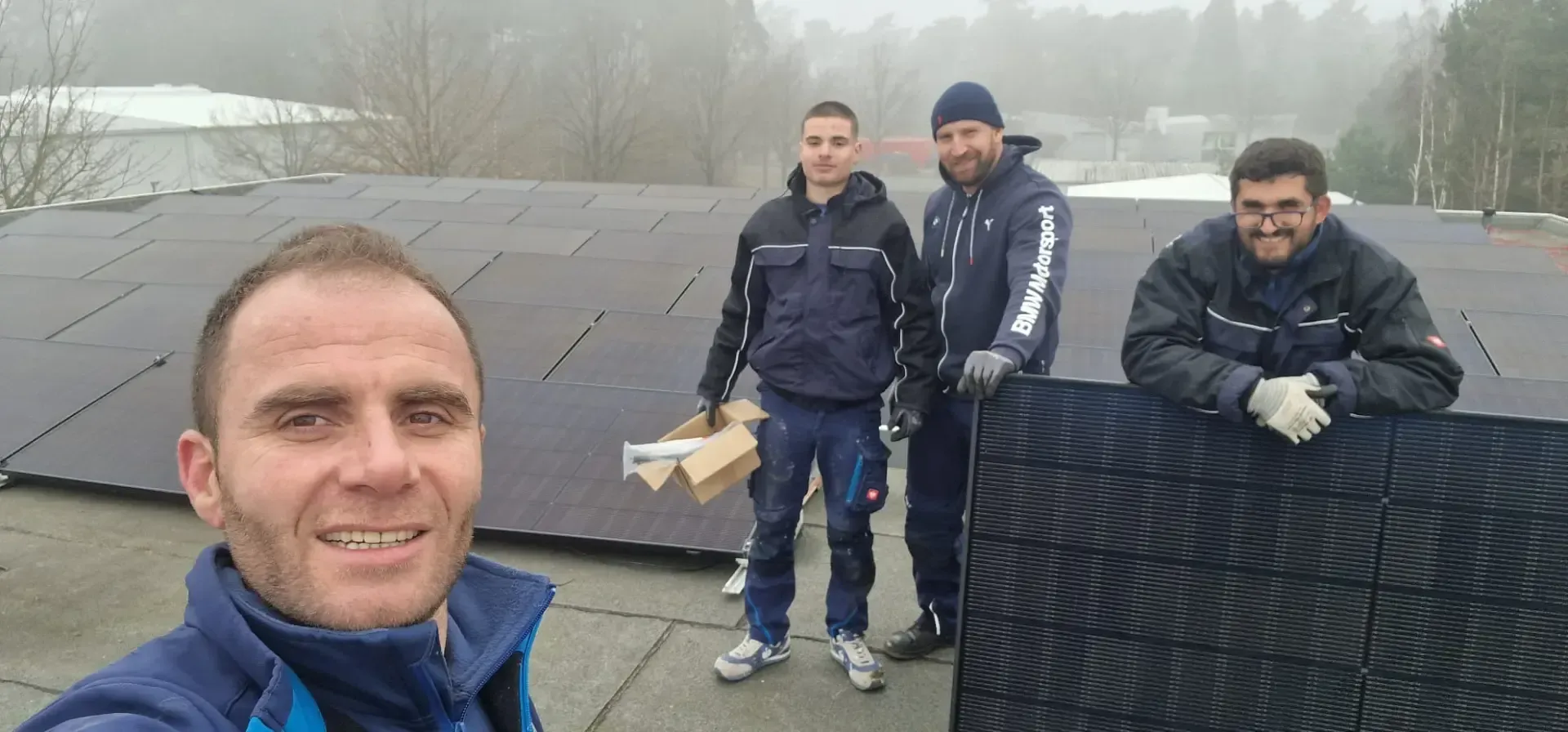 Eine Gruppe von Männern steht auf einem Dach und hält ein Solarpanel.