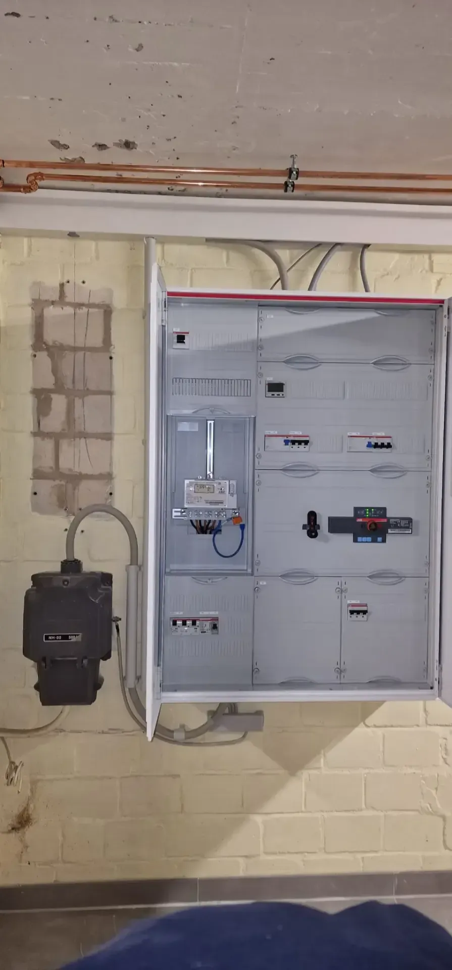 An einer Ziegelwand hängt ein großer Elektrokasten.