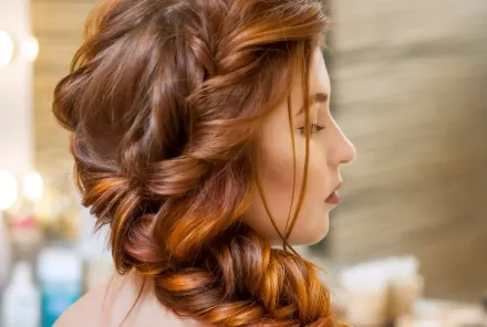 Una mujer con cabello largo y rojo lleva un peinado trenzado.