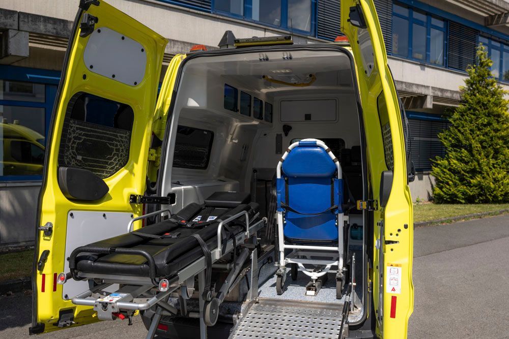 Ein Transportwagen mit offener hinterer Tür und einer Trage auf der Ladefläche.