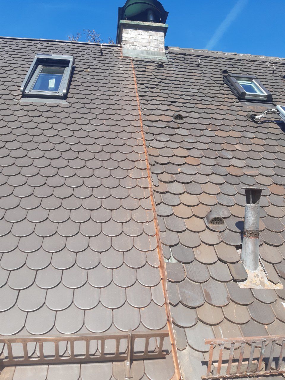 Graues Hausdach mit Dachgaube vor klarem, blauem Himmel