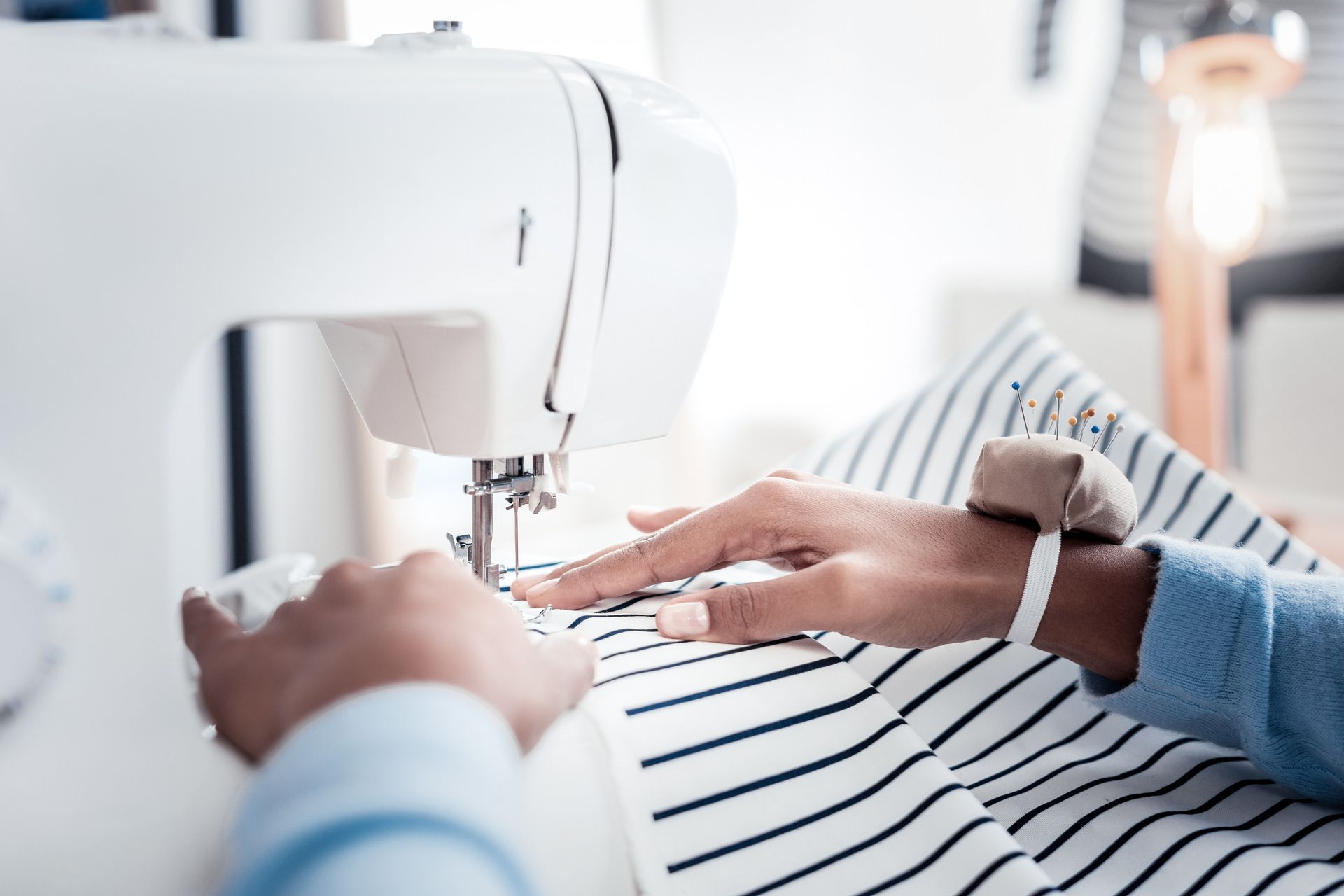Una persona está usando una máquina de coser para coser una tela rayada.