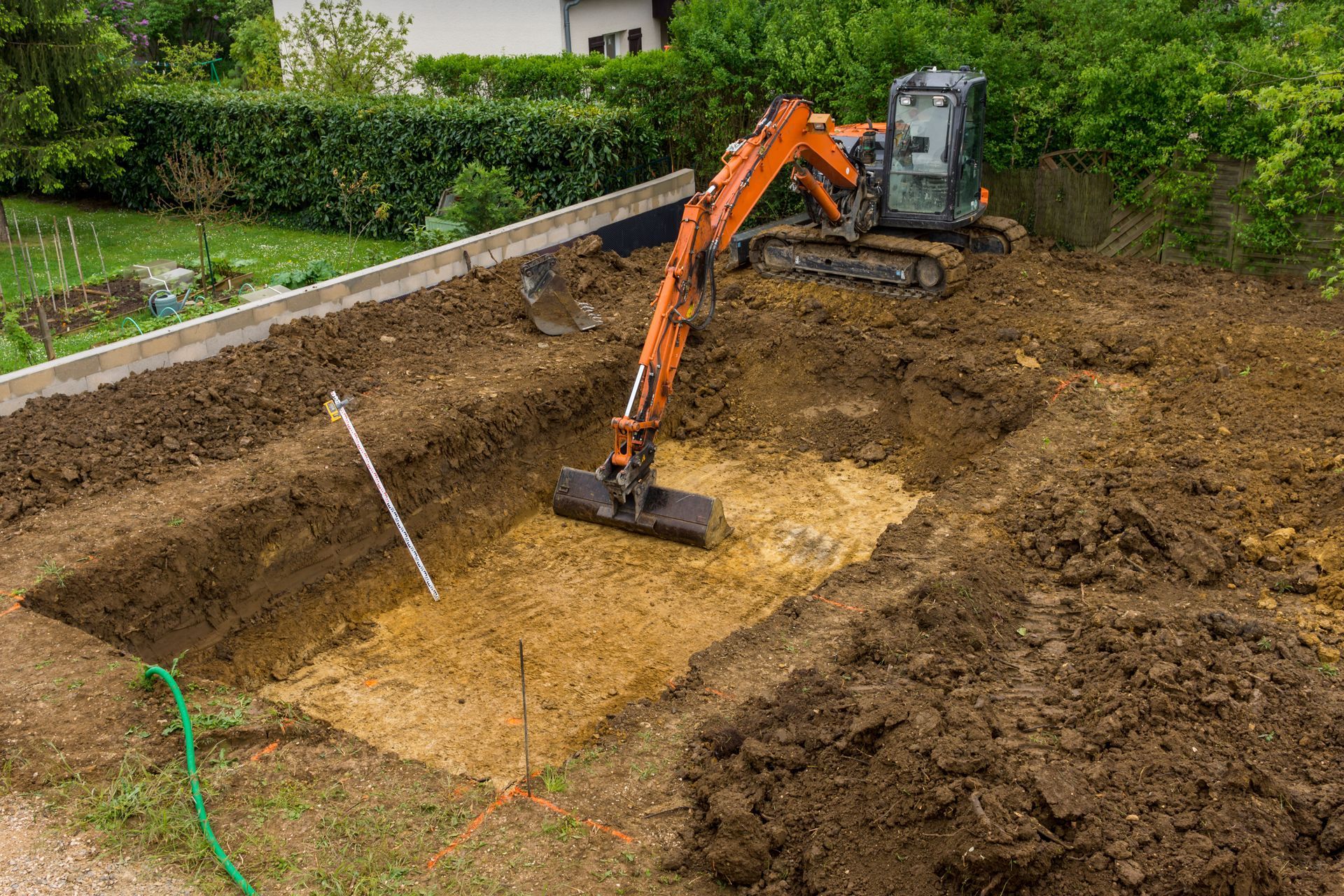 Une mini-pelle creuse une grande fosse dans le cadre de la construction d'une piscine.