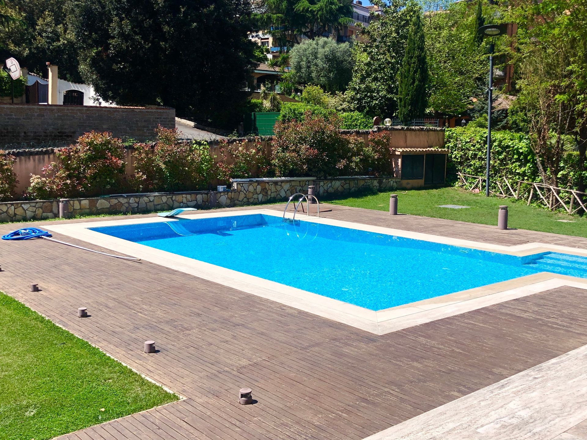 Piscine creusée entourée d'une terrasse en bois et d'un jardin verdoyant.