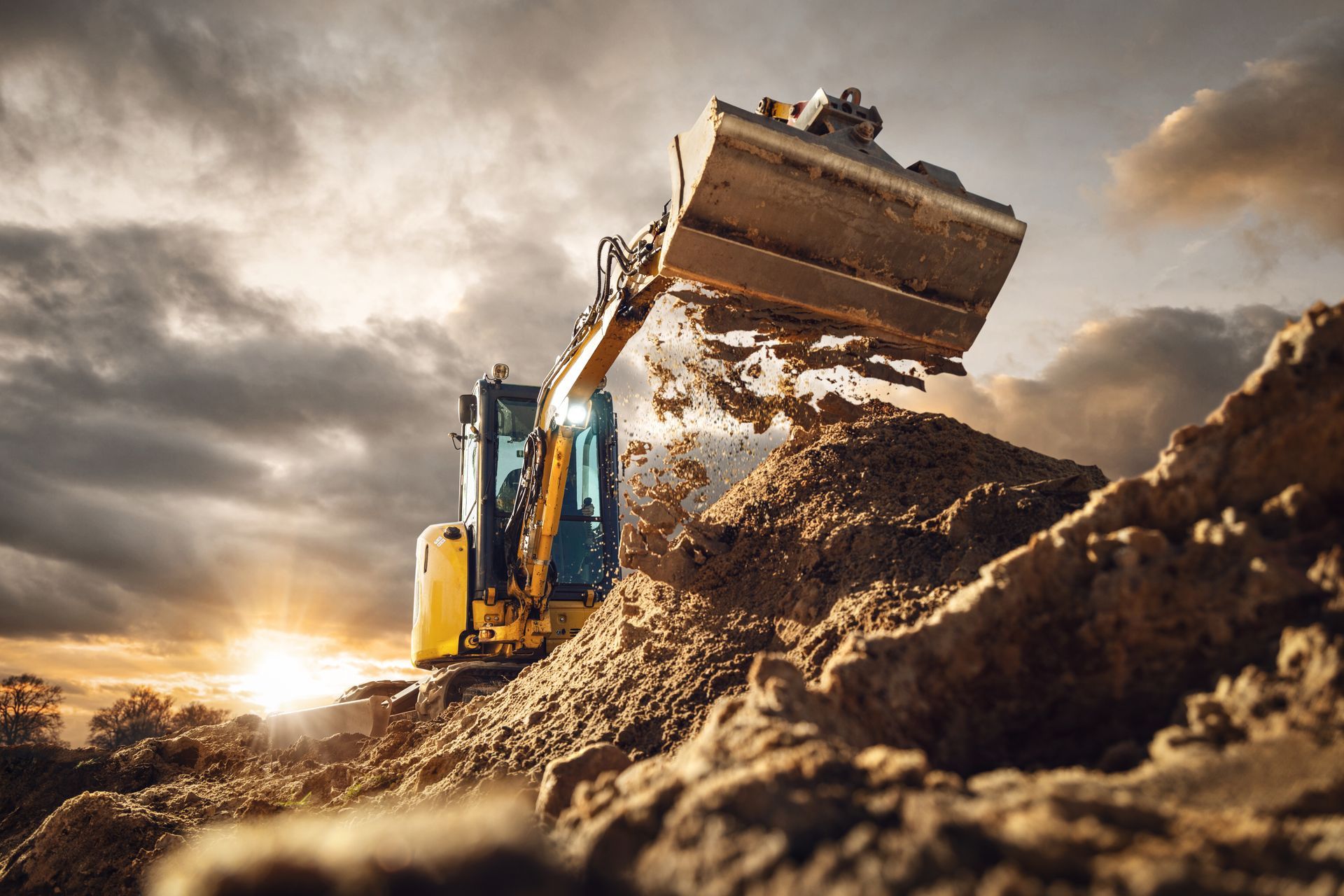 Une pelleteuse jaune déverse de la terre sur un chantier de construction.