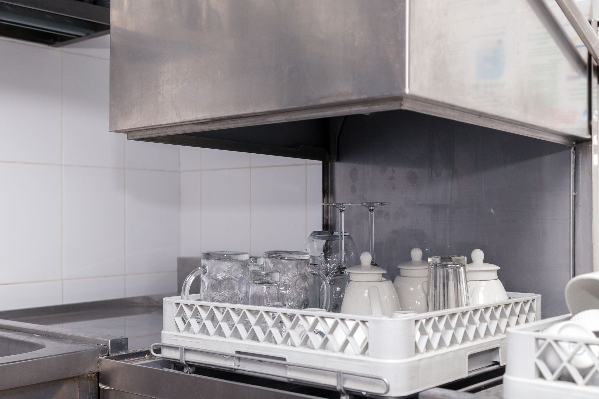 Un lave-vaisselle professionnel avec des verres et carafes dedans.
