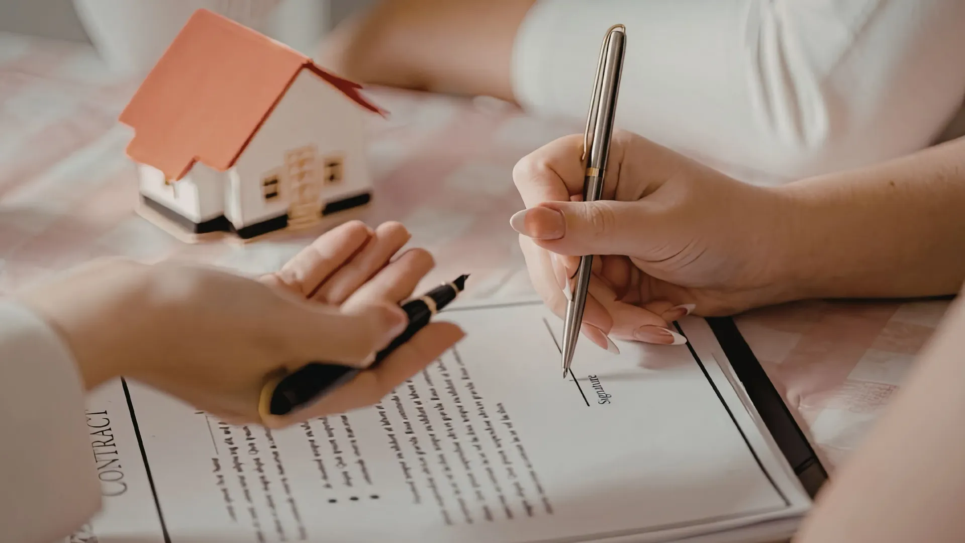 Persona con traje entregando llaves con amuleto de casa a otra persona.
