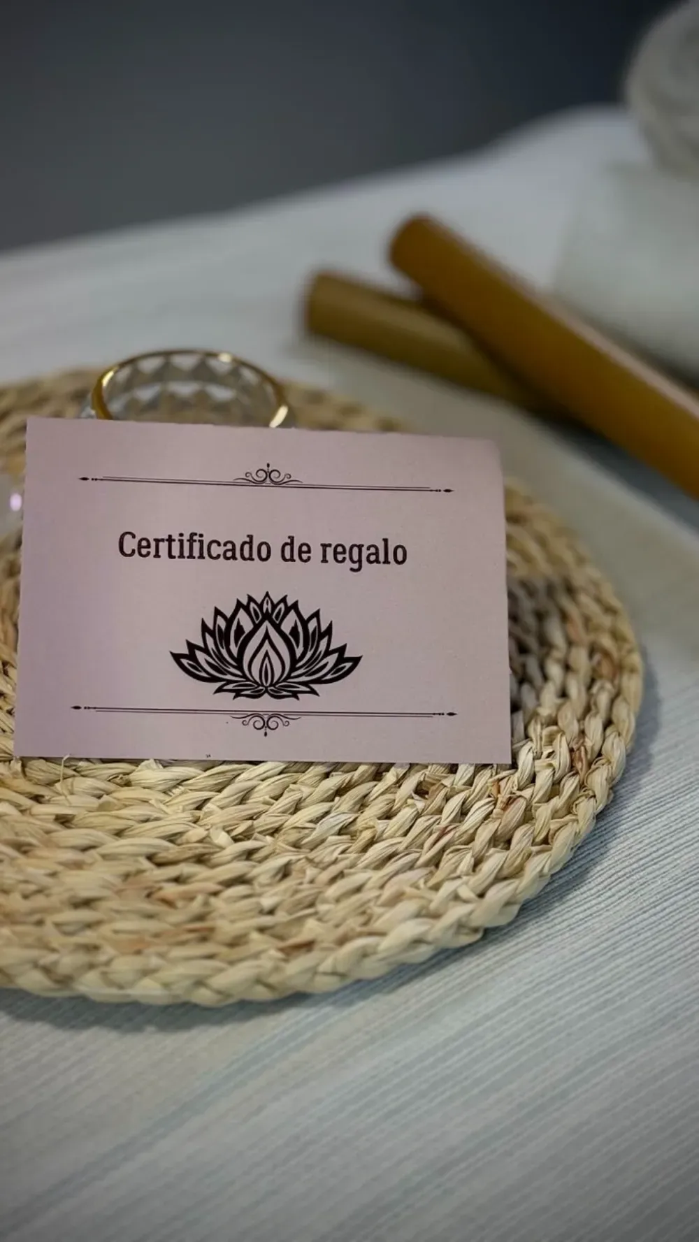 Un certificado de regalo de color rosa claro con el logotipo de una flor de loto reposa