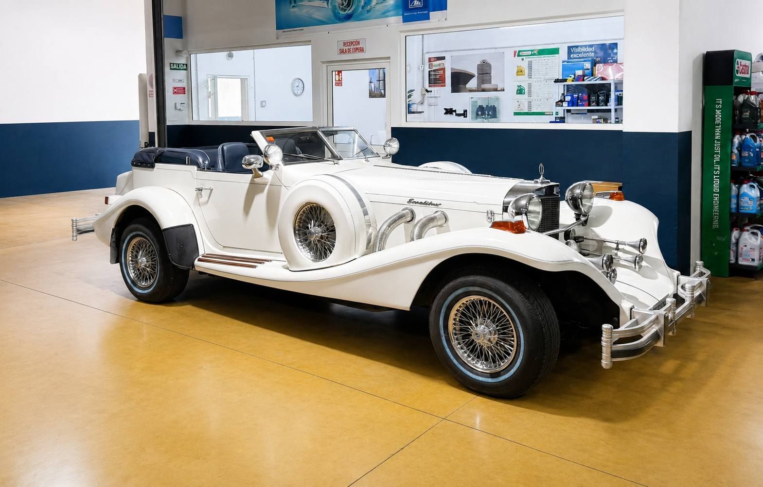 Coche deportivo descapotable clásico blanco expuesto en el interior de una sala de exposición, con motor a la vista.