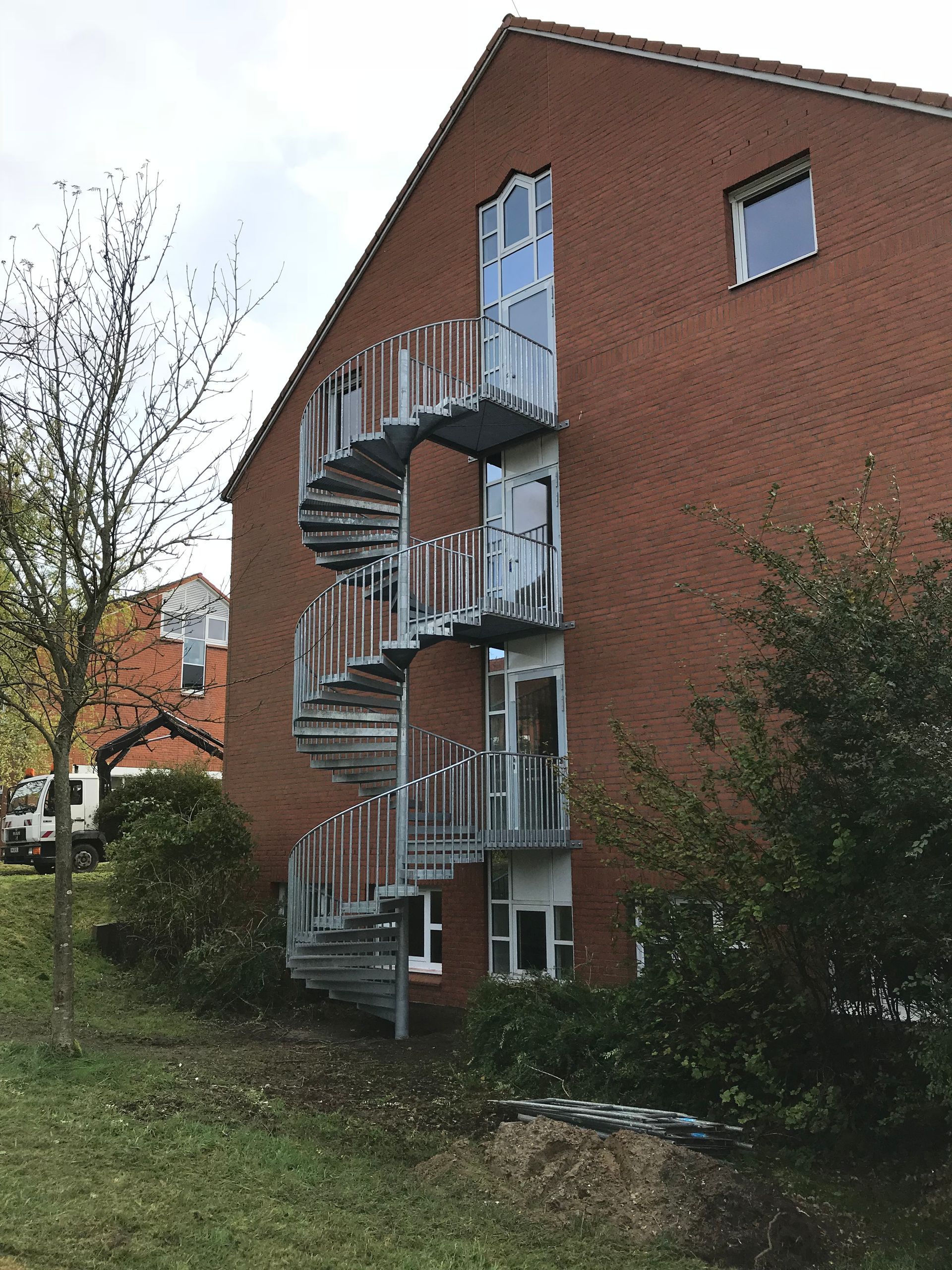 Außenansicht eines roten Backsteingebäudes mit einer daran befestigten spiralförmigen Metalltreppe.