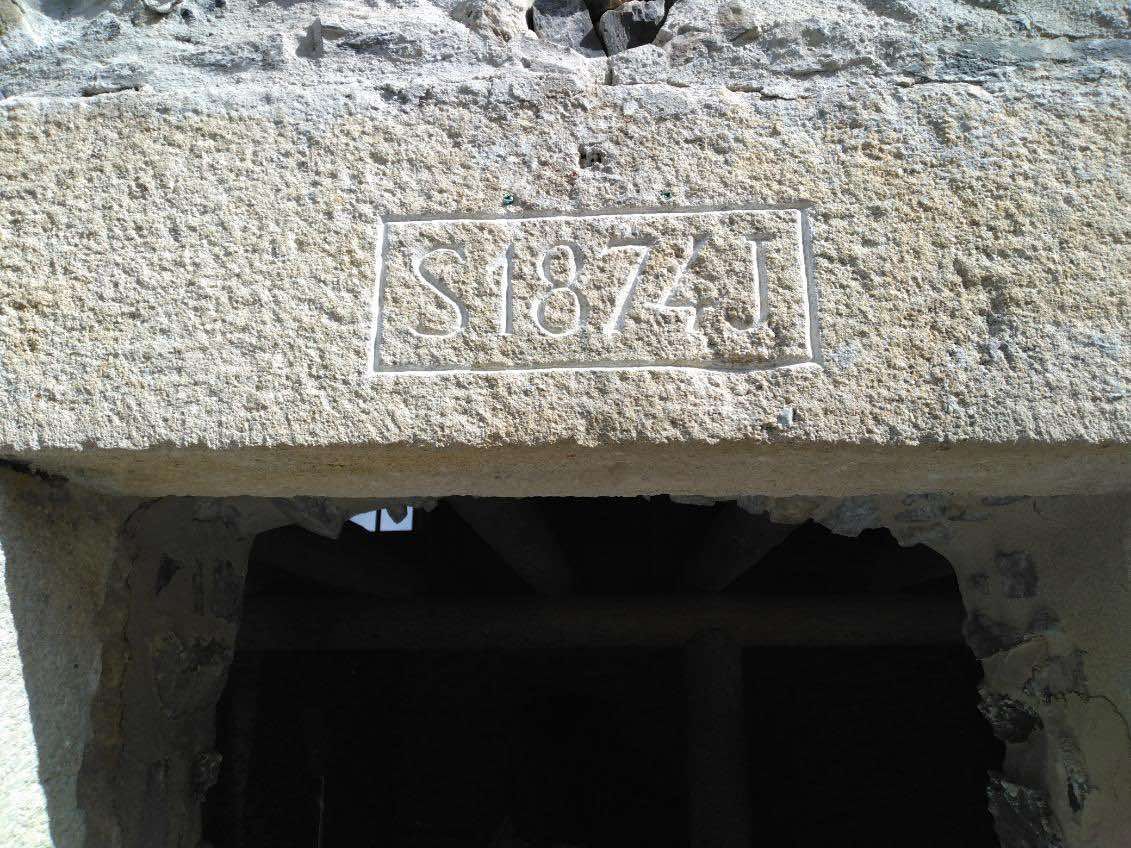 Linteau en pierre portant une date gravée au-dessus d'une porte sombre.