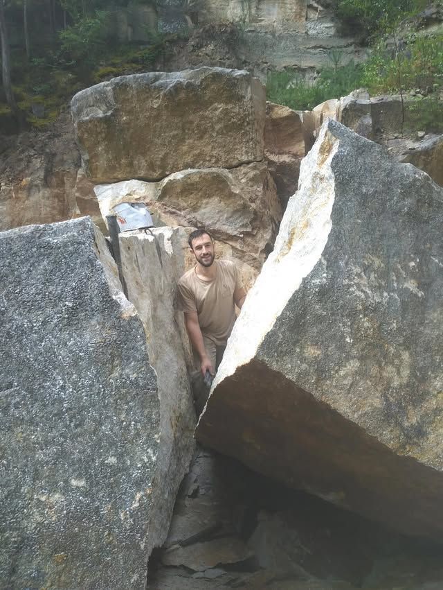 Un homme, debout entre de gros rochers dans un canyon rocheux.