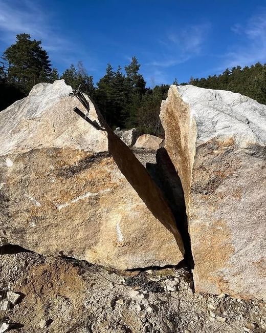 Gros blocs de granit fendus dans une clairière ensoleillée sous un ciel bleu