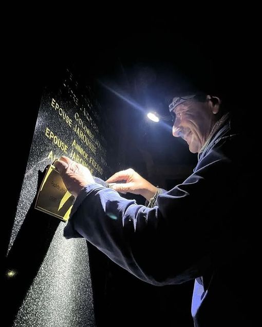Une personne utilisant une lampe de poche pour inspecter une plaque sombre la nuit.