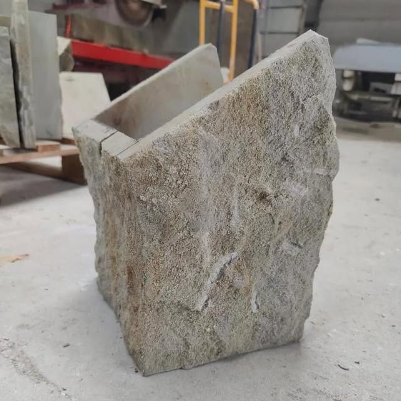 Conteneur en pierre brute avec une ouverture en biais sur une table d'atelier.
