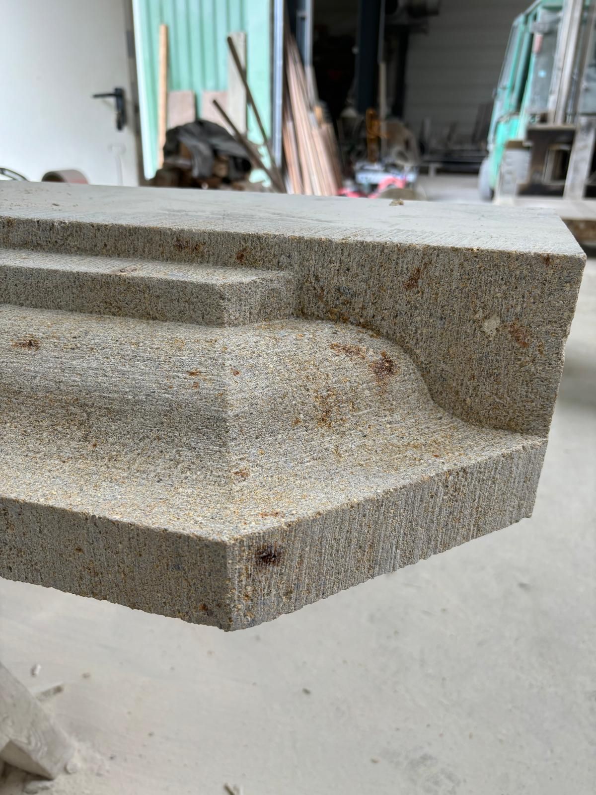 Bloc de marche en béton gris à bord arrondi, présenté dans un atelier ou sur un chantier.