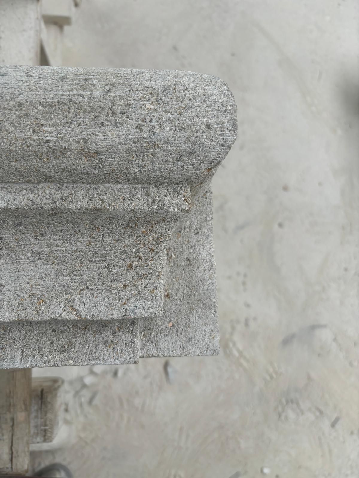 Détail de balustrade en pierre grise sur un mur en béton clair