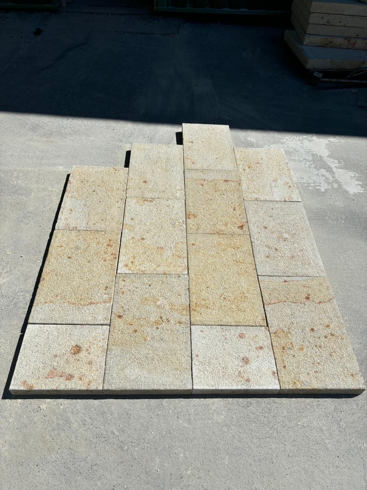 Empilement de pavés clairs disposés en motif rectangulaire sur une surface sombre à l'extérieur