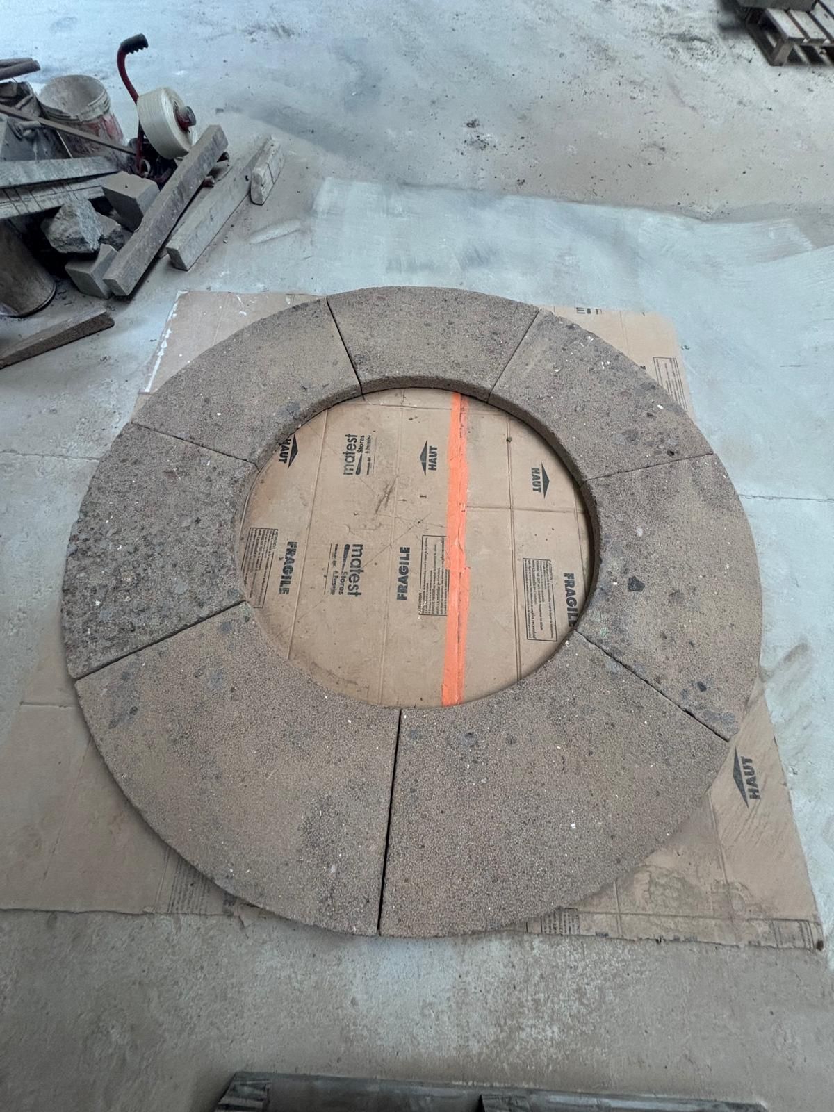 Motif de pavage en pierre ronde avec un centre en carton et une ligne orange sur un sol en béton