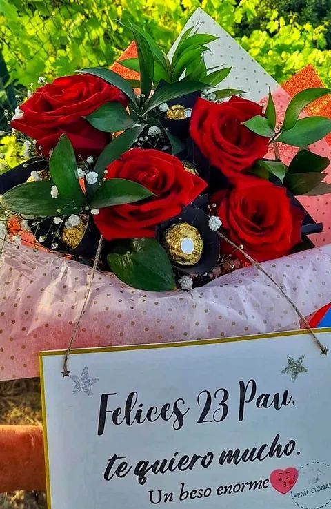 A bouquet of red roses with a sign that says felices 23 par te quiero mucho