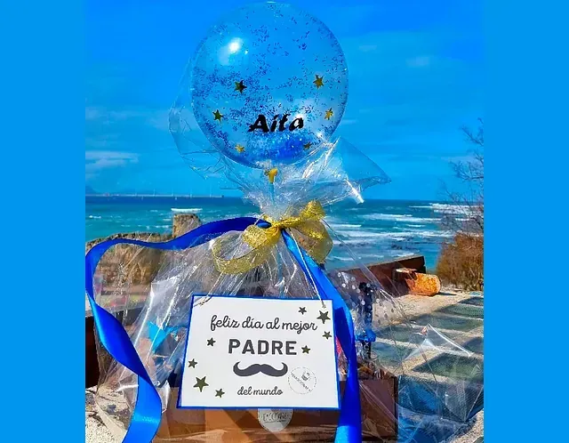 Un globo azul con la palabra padre está encima de una caja de regalo.