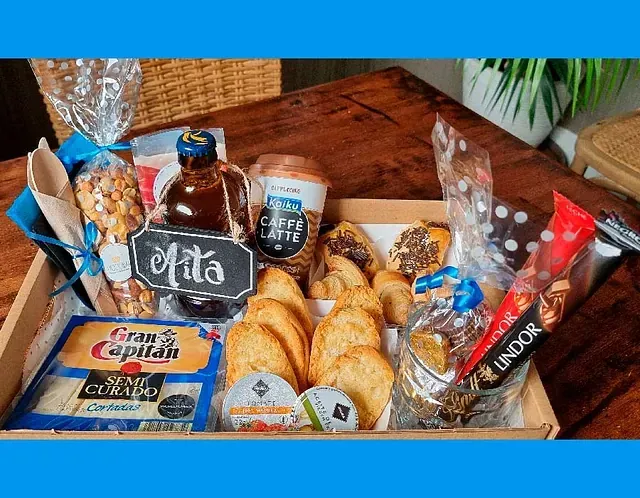 Una caja llena de una variedad de alimentos y bebidas está sobre una mesa de madera.