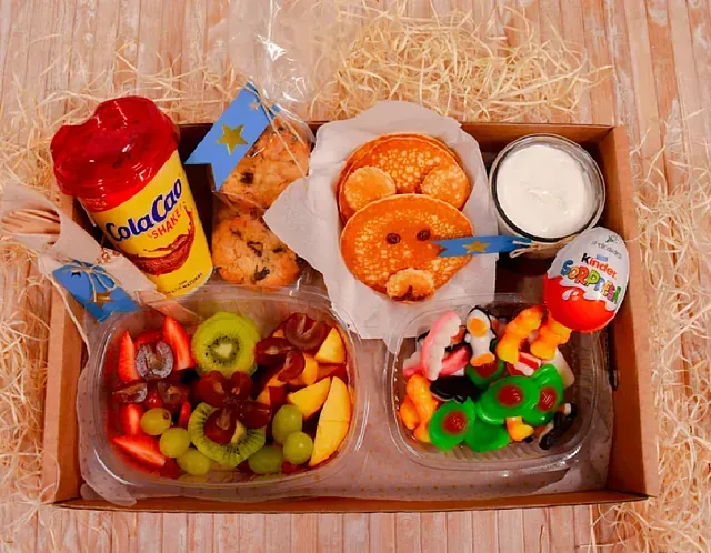 Una caja llena de una variedad de alimentos y bebidas, incluido un huevo Kinder.
