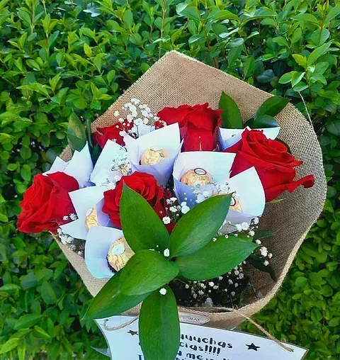 Un ramo de rosas rojas y bombones Ferrero Rocher.