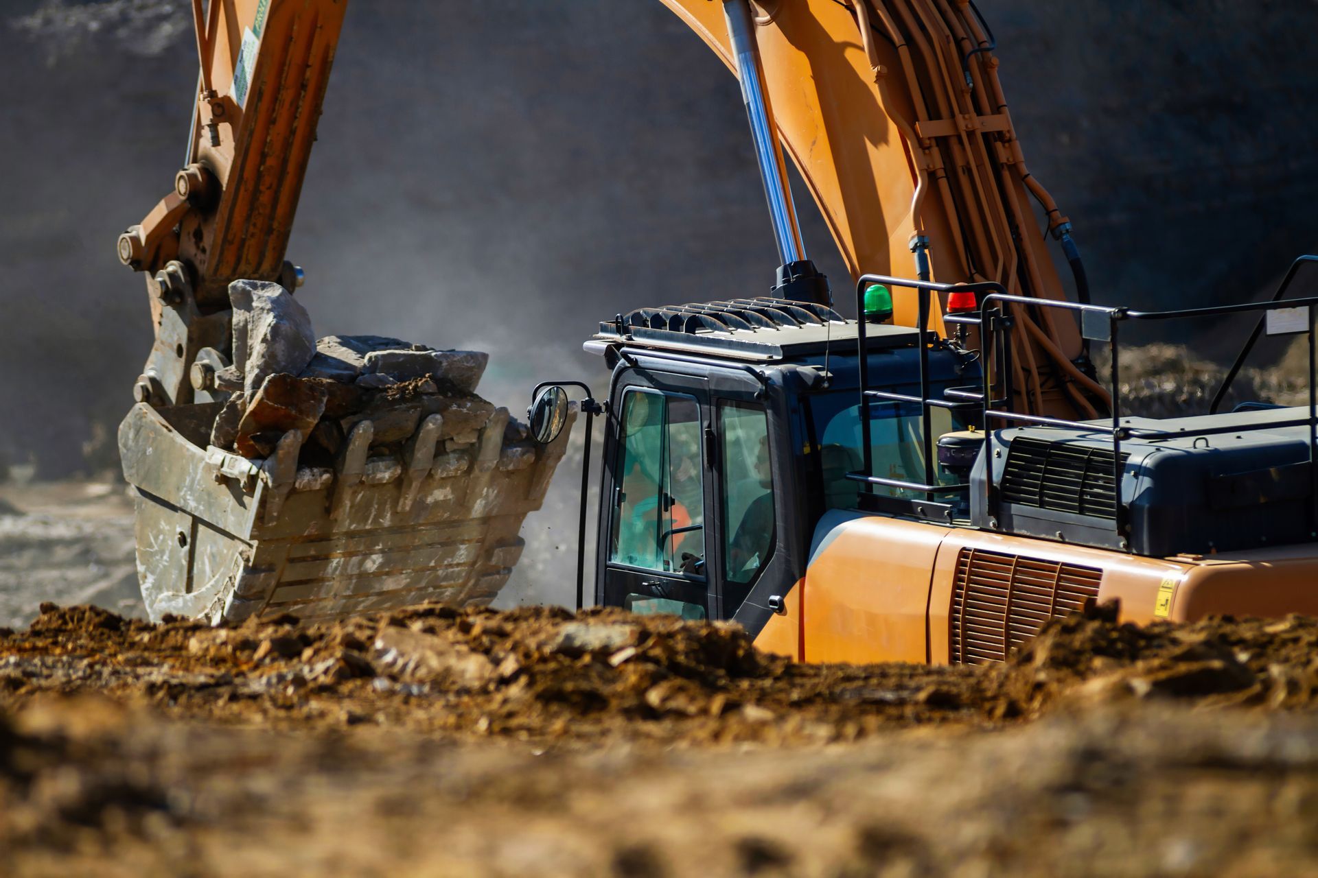 Une pelleteuse orange ramasse de la terre en extérieur.