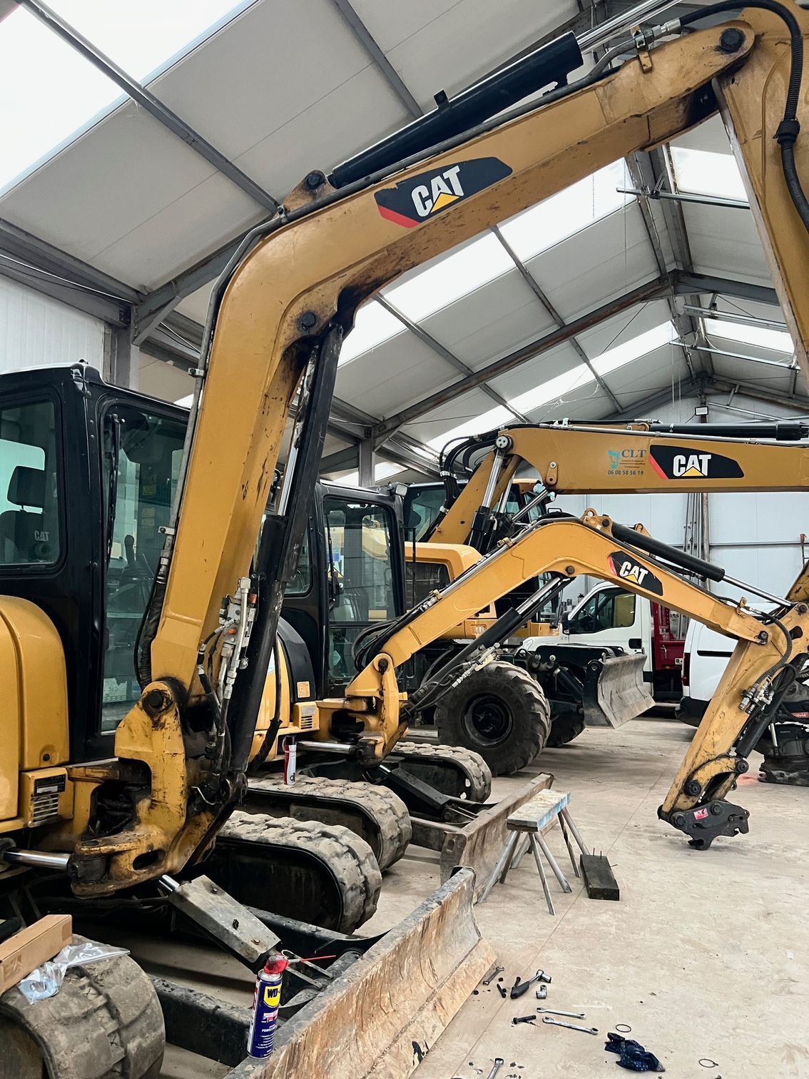 Des pelles hydrauliques Caterpillar jaunes à l'intérieur d'un garage.