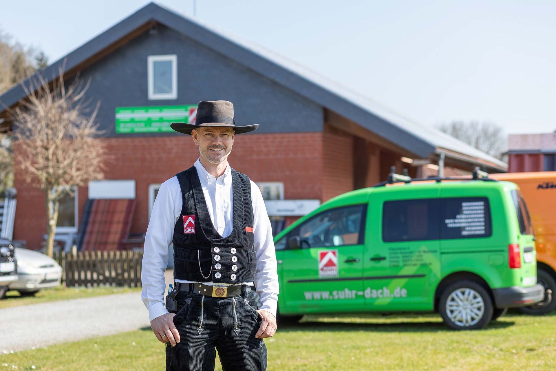 Ein Mann mit Hut steht vor einem grünen Lieferwagen.