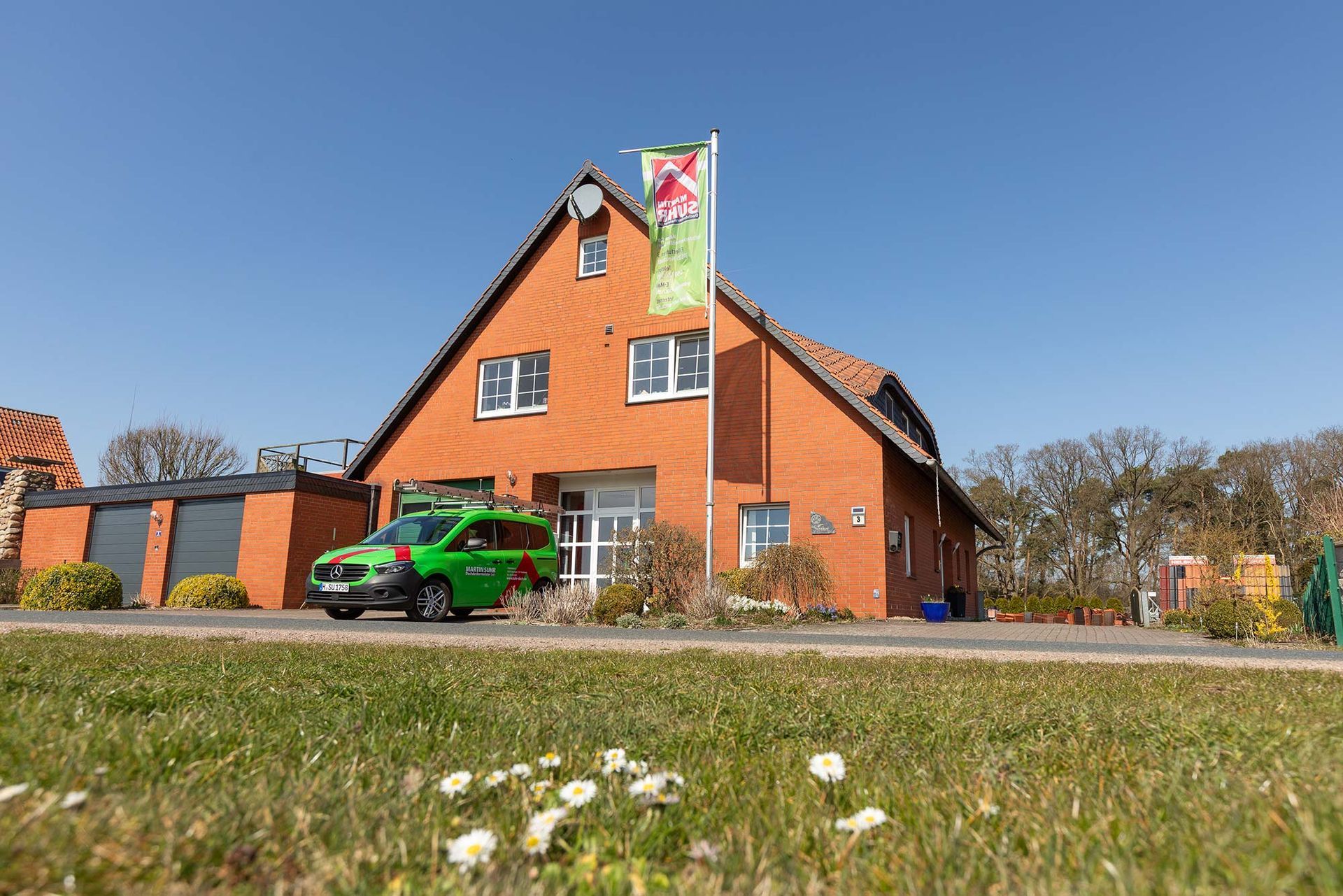 Ein grünes Auto parkt vor einem Backsteinhaus.