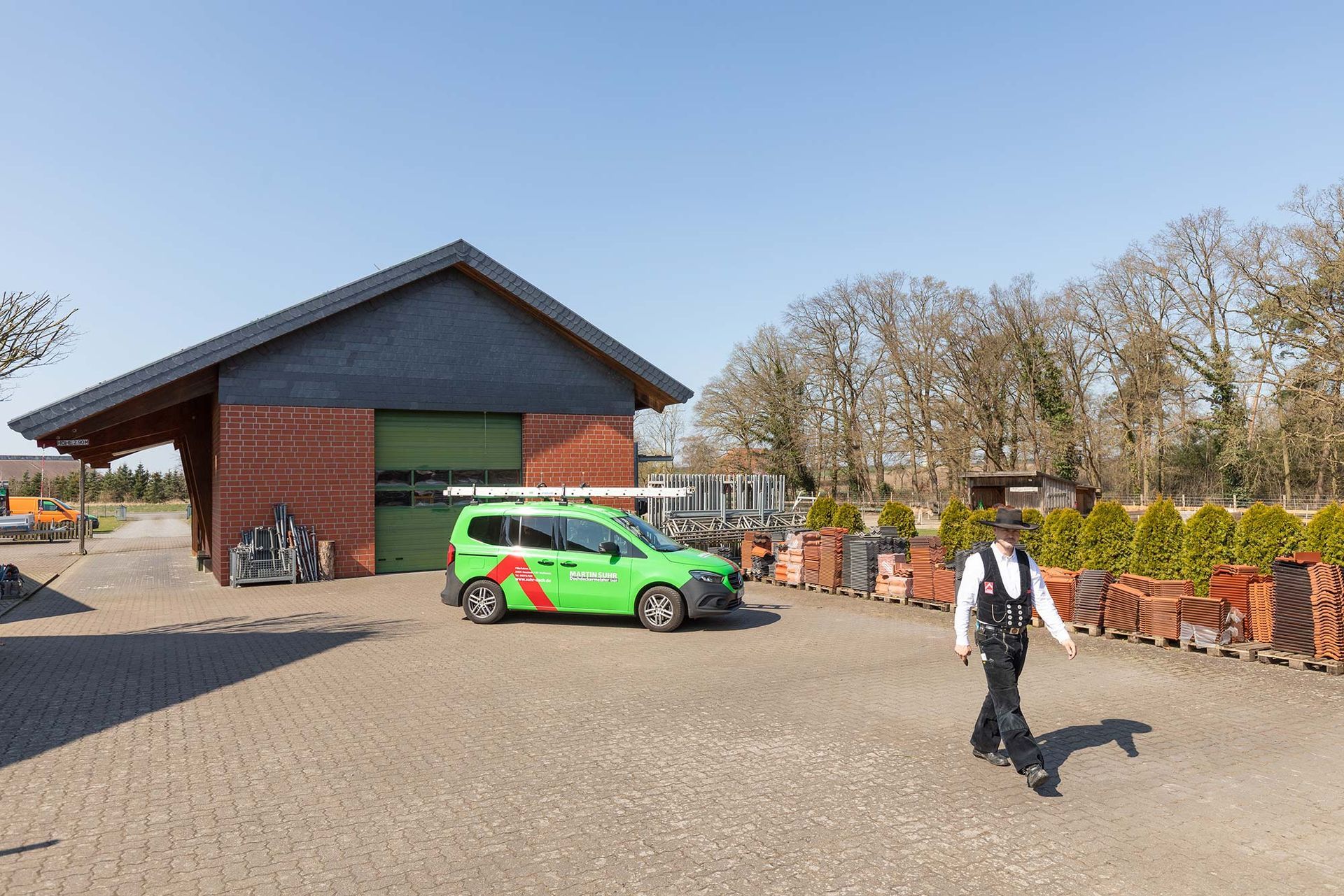 Ein Mann läuft vor einem grünen Lieferwagen her, der vor einem Gebäude geparkt ist.