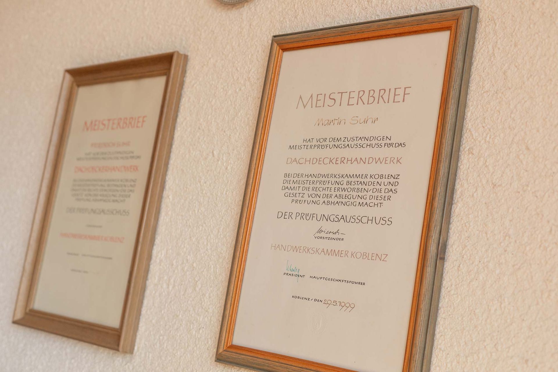 Zwei gerahmte Papiere an einer Wand, von denen eines sagt Meisterbrief