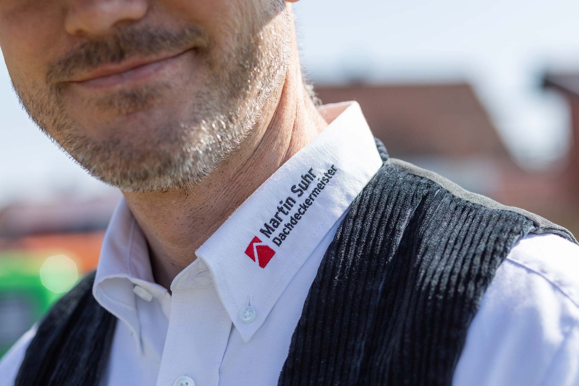 Ein Mann mit Bart trägt ein weißes Hemd und eine schwarze Weste.