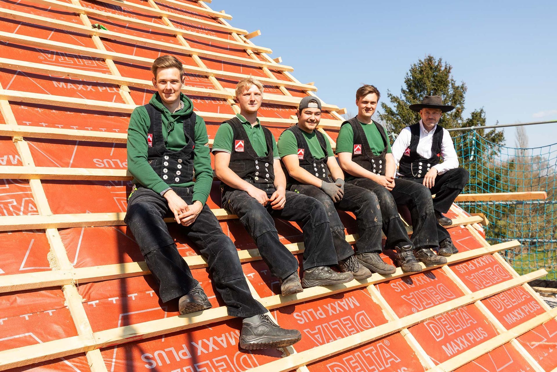 Eine Gruppe Bauarbeiter sitzt auf dem Dach eines Gebäudes.