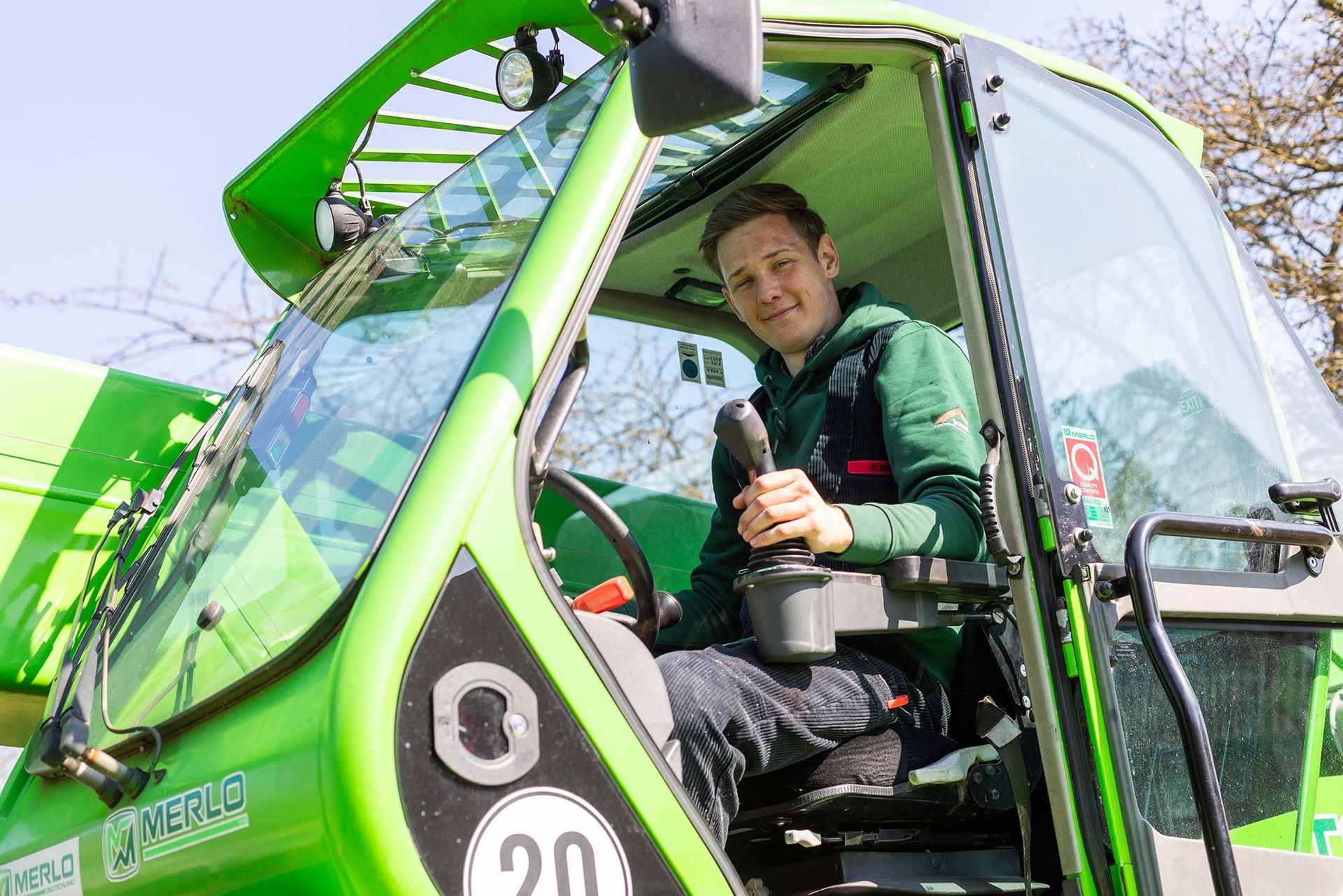 Ein Mann sitzt auf dem Fahrersitz eines grünen Traktors.
