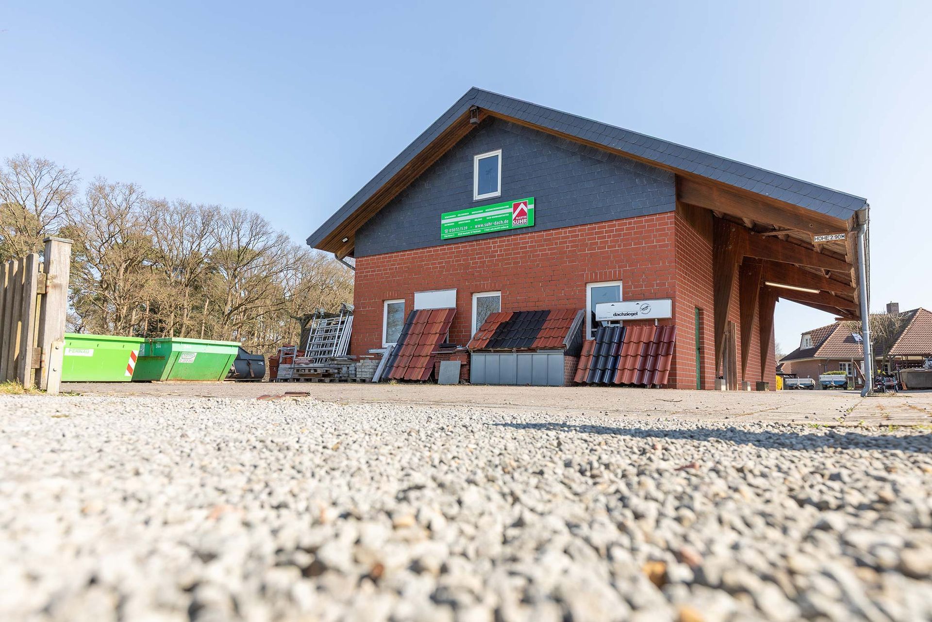 Ein großes Backsteingebäude mit einem Dach und viel Kies davor.