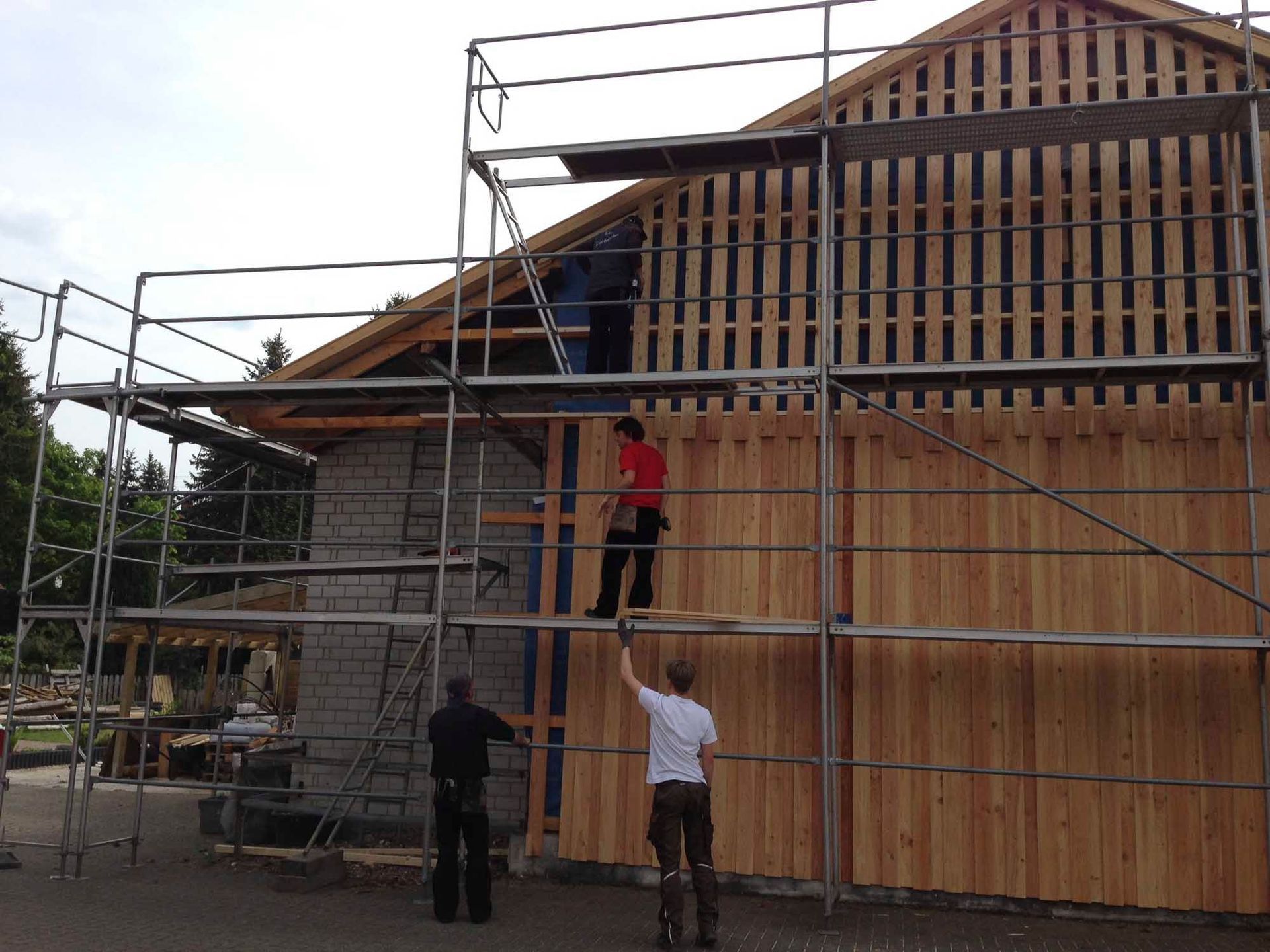 Zwei Männer stehen auf einem Gerüst an der Seite eines Gebäudes