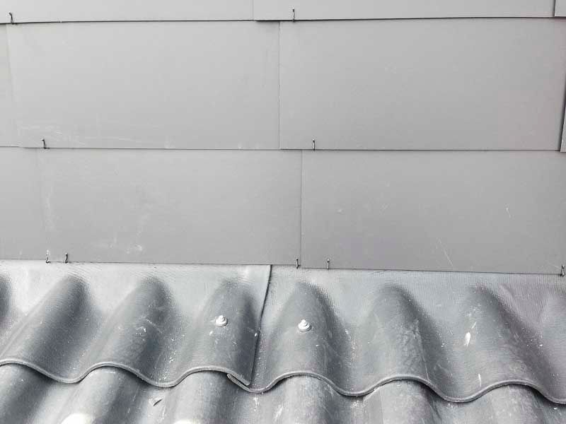 Eine Nahaufnahme eines grauen Dachs mit einer weißen Wand im Hintergrund.