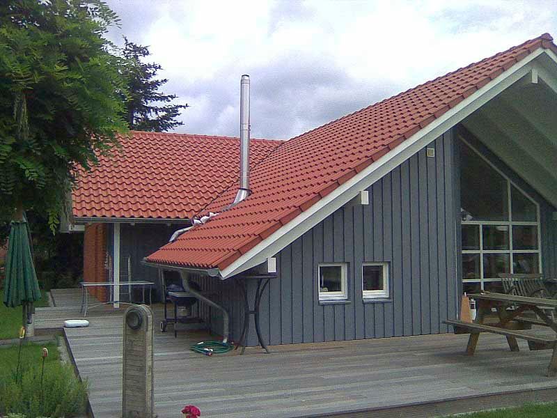 Ein Haus mit einem roten Ziegeldach und einer Holzterrasse