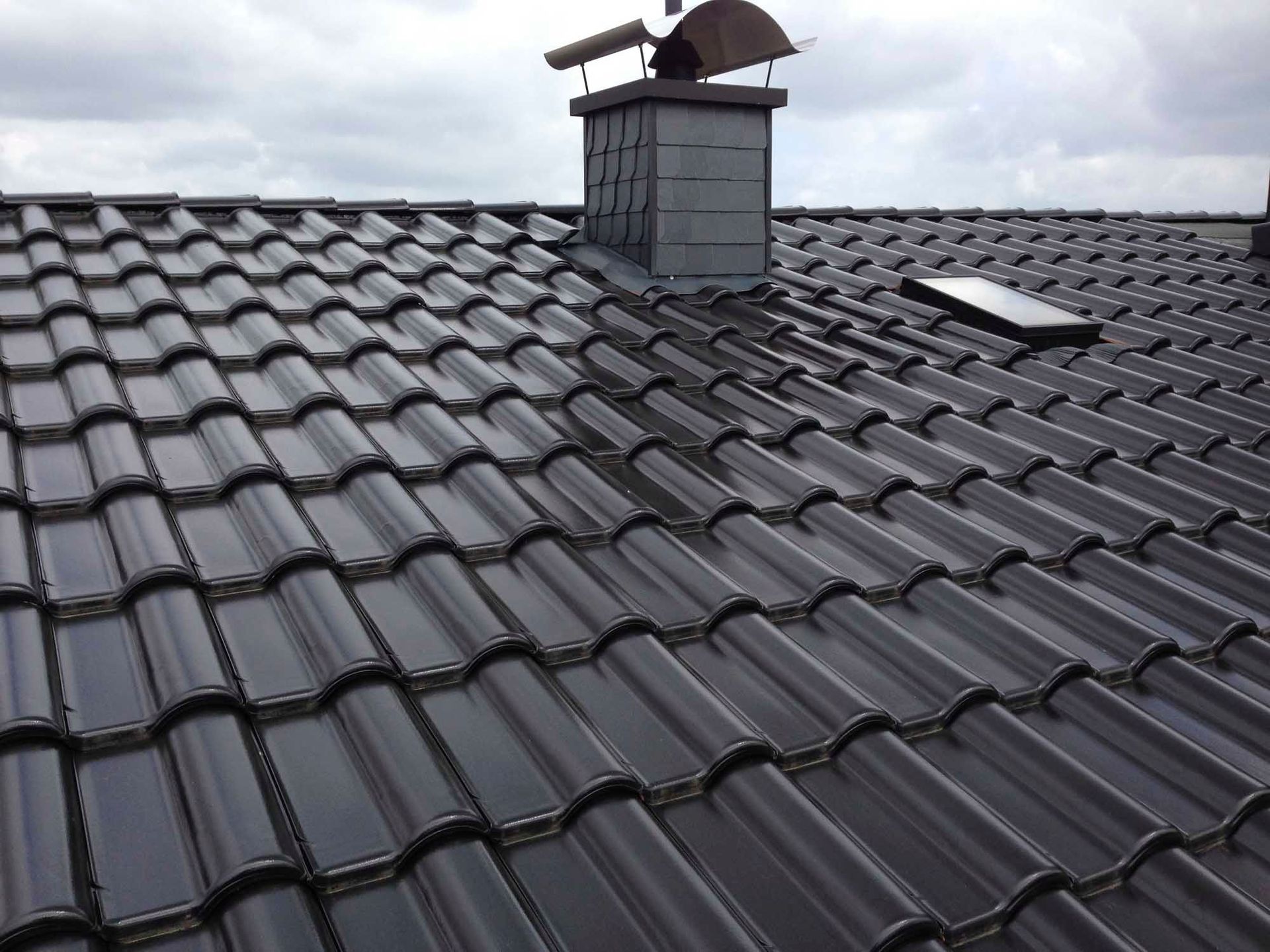 Ein schwarzes Ziegeldach mit einem Schornstein darauf