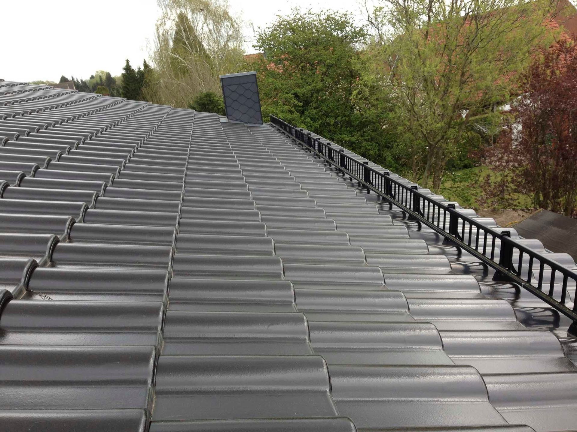 Ein Dach mit vielen Ziegeln darauf und Bäumen im Hintergrund.