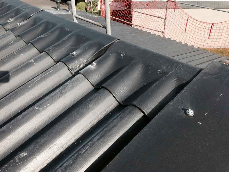 Eine Nahaufnahme eines schwarzen Daches mit einem roten Zaun im Hintergrund