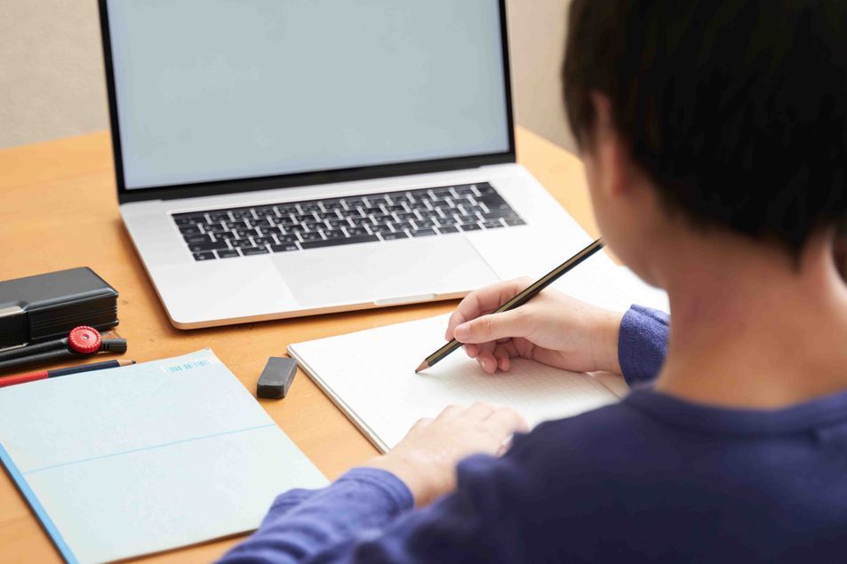 Persona escribiendo en un escritorio con una computadora portátil abierta cerca