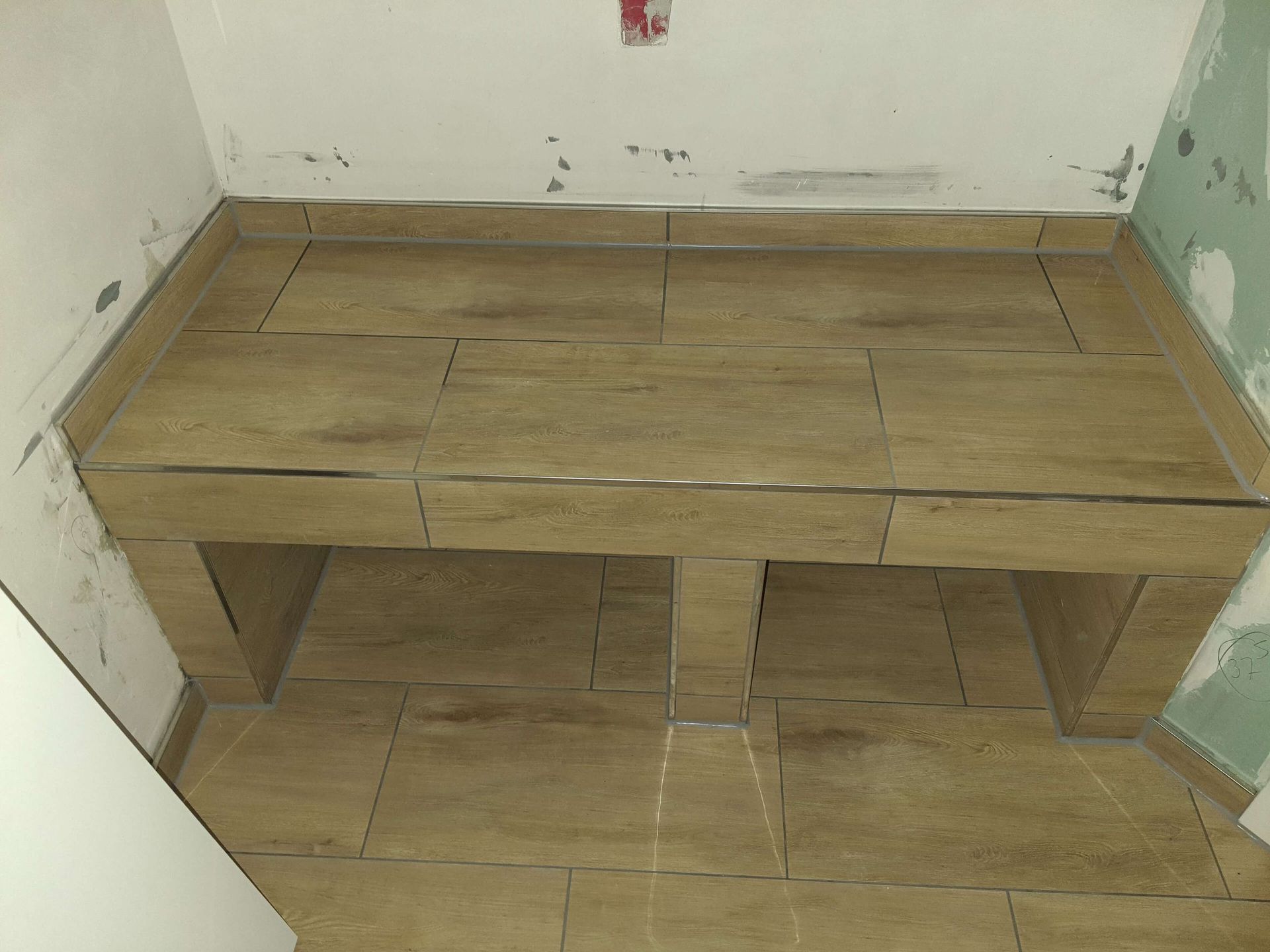 Eine Zimmerecke mit gefliestem Boden und weißer Wand.