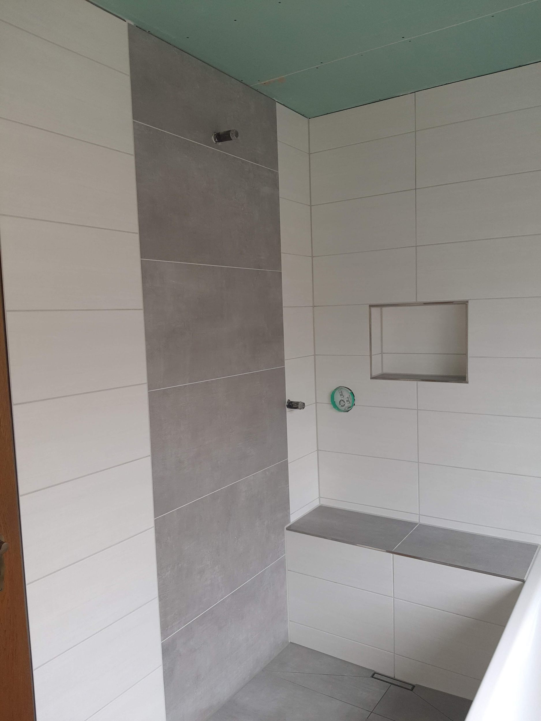 Ein Badezimmer mit weißen Fliesen und einer Bank in der Ecke.