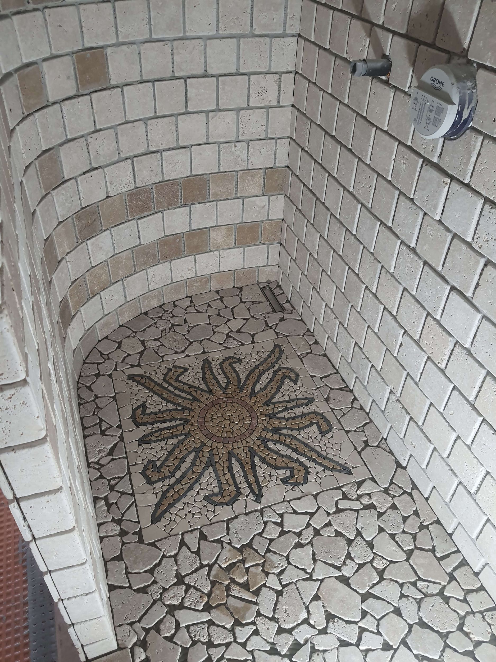 Eine Duschkabine mit Mosaikmuster auf dem Boden.